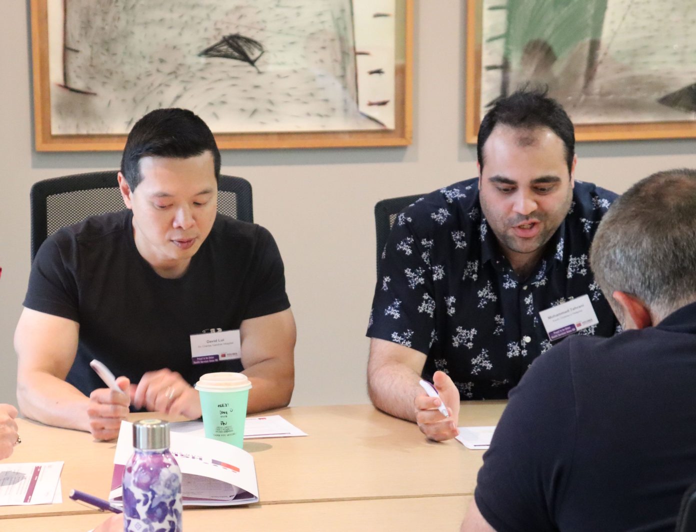 Two male union members sit at a table discussing the log of claims for their Union Agreement.