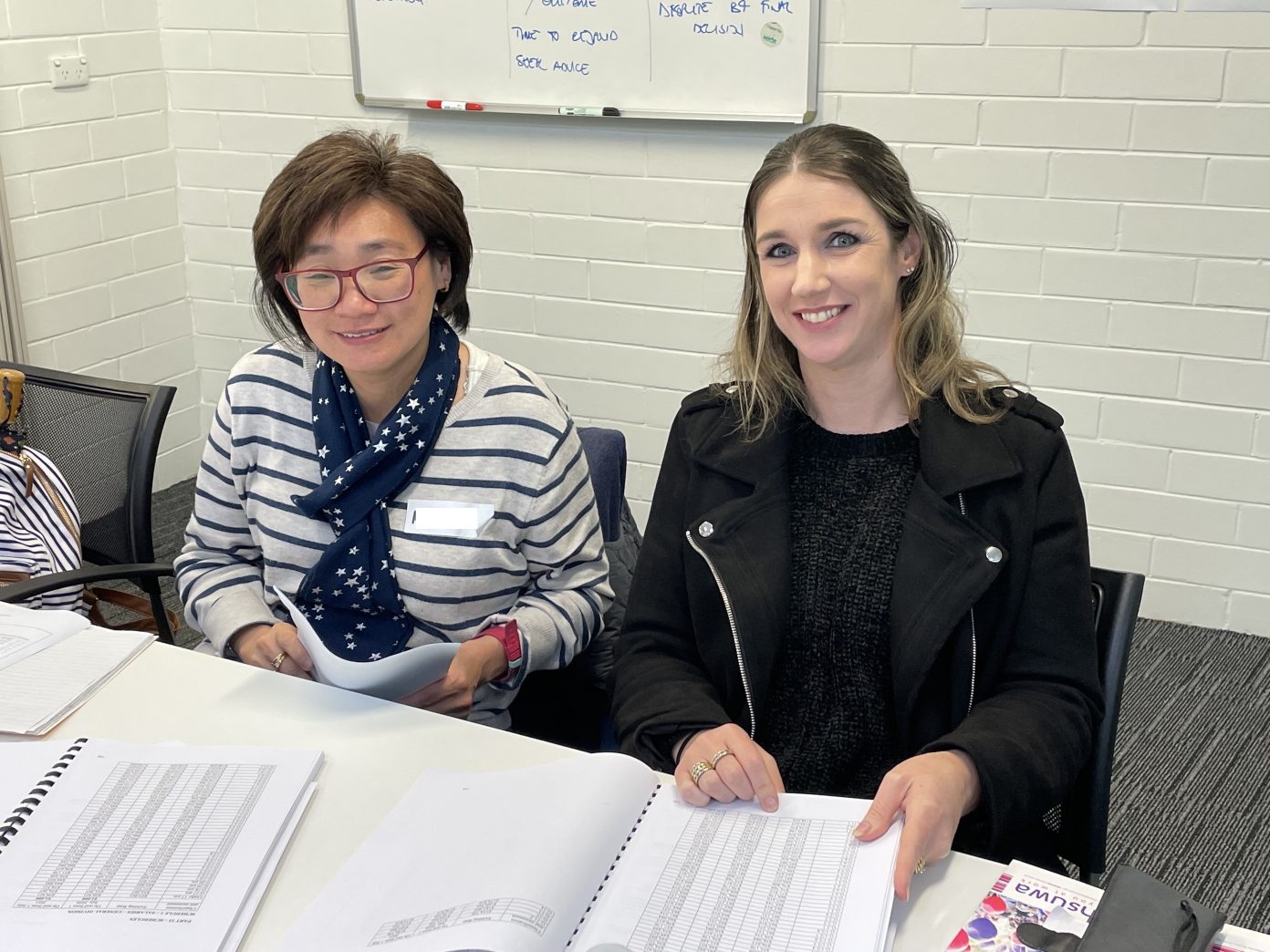 Two women sit at a desk with Union Agreements in front of them at a HSUWA Workrights training course.