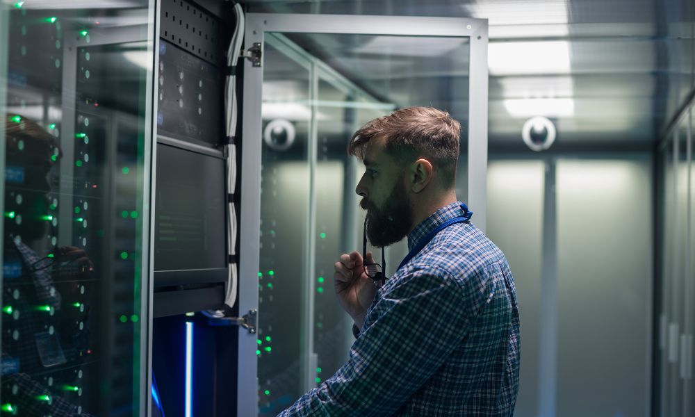 A male IT specialist looks into a server cabinet.