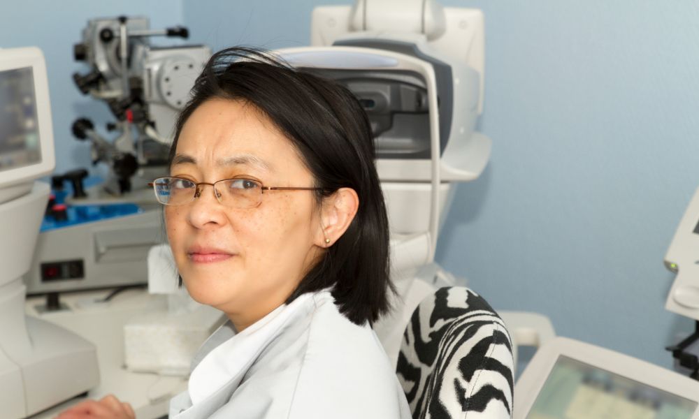 A female orthoptist sits in front of her equipment.
