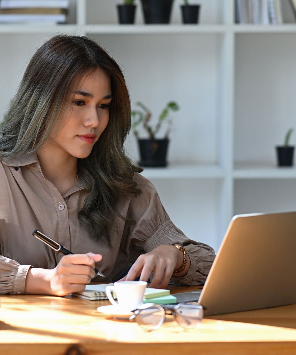 Female professional sits at her laptop making notes.