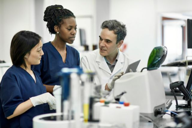 Three pathology lab workers stand together discussing a matter.