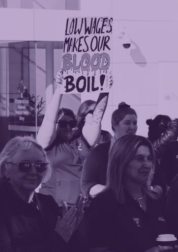 ACL Members at a stop work meeting. One holds up a sign that says, "Low wages makes our blood boil"