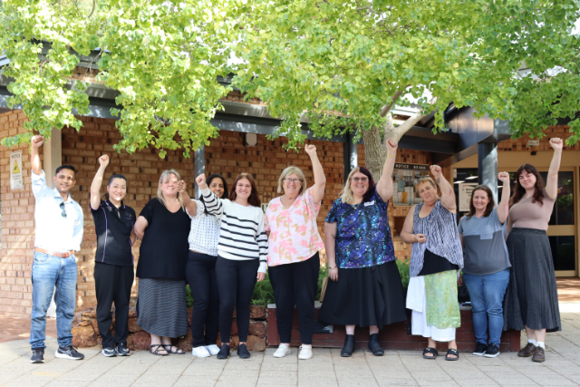 A group of HSUWA Members, with their fists in the air under a leafy canopy at WorkRights training.