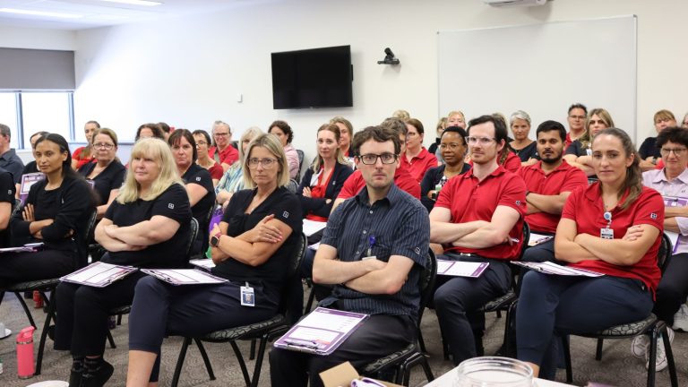 Members sit in a meeting with their arms folded.